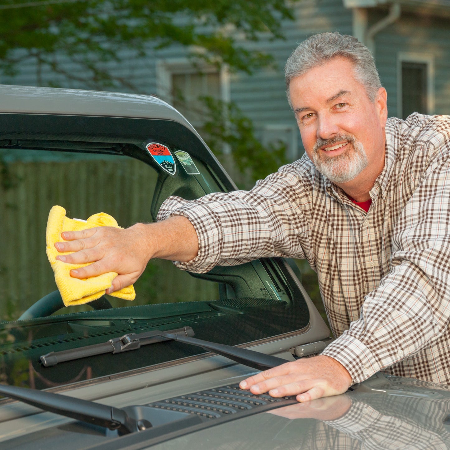 A car owner polishes the glass after applying souvenir stickers to the windshield with sticker shield.